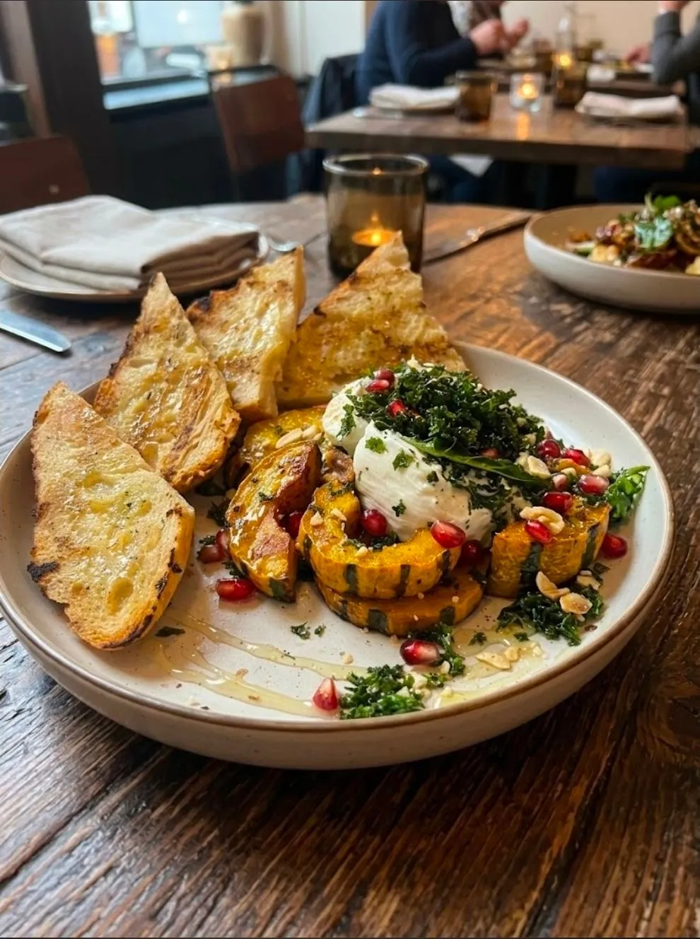 Roasted seasonal squash topped with burrata, pomegranate and herbs, served with grilled sourdough