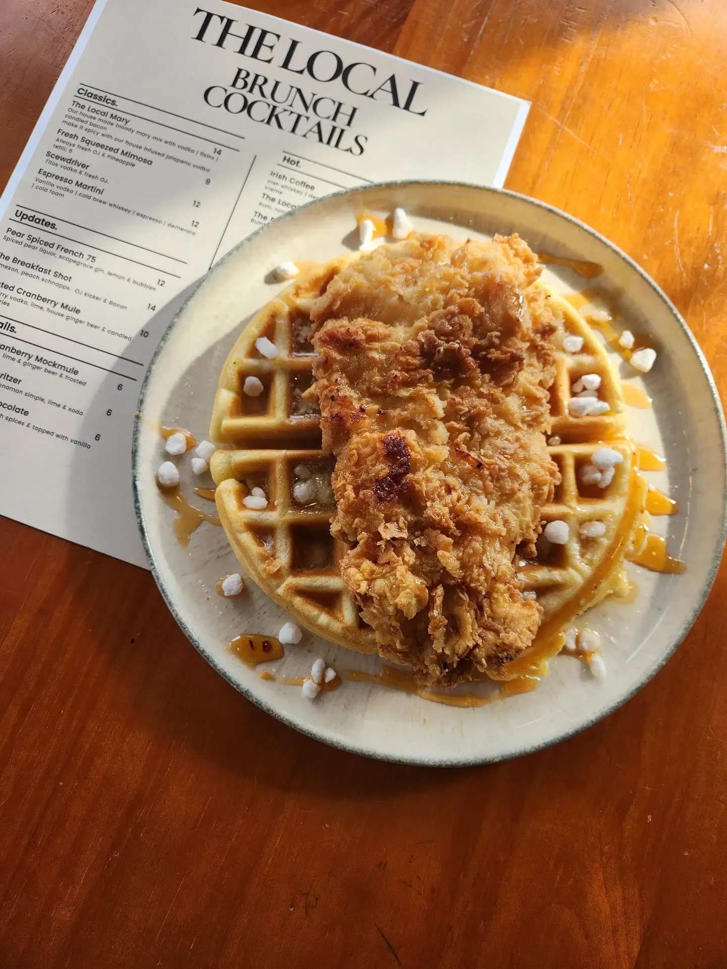 Crispy fried chicken over waffles, drizzled with syrup, from The Local’s brunch menu